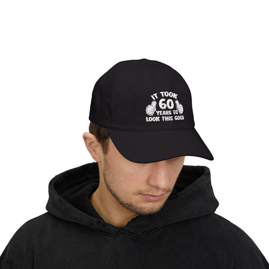 baseball cap with white embroidery reading “It Took 60 Years To Look This Good” with two thumbs-up graphics