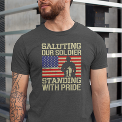 ‘Saluting Our Soldier Standing With Pride’ text, American flag background, and soldier silhouette with saluting family