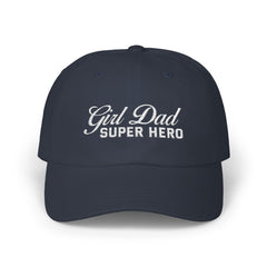Woman wearing a black hat with mixed-script embroidered text reading “Girl Dad Super Hero” standing against a chain-link fence