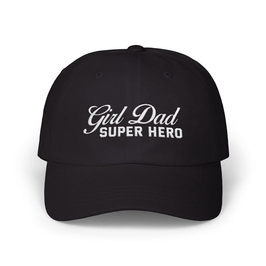 Woman wearing a black hat with mixed-script embroidered text reading “Girl Dad Super Hero” standing against a chain-link fence