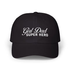 Woman wearing a black hat with mixed-script embroidered text reading “Girl Dad Super Hero” standing against a chain-link fence