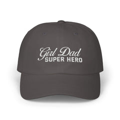 Woman wearing a black hat with mixed-script embroidered text reading “Girl Dad Super Hero” standing against a chain-link fence